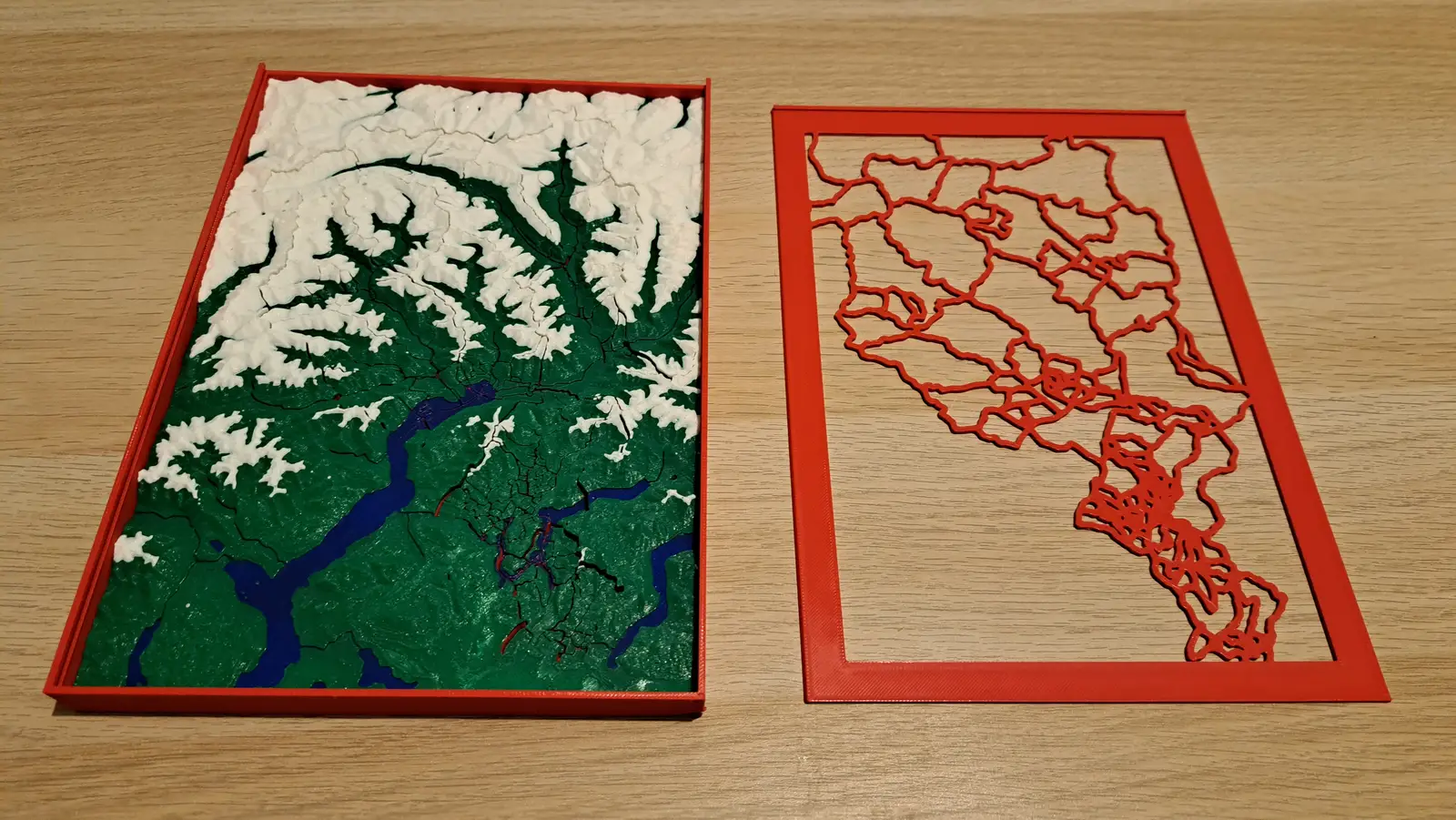 A Ticino relief puzzle in a red tray beside a red frame cut with the outlines of its pieces