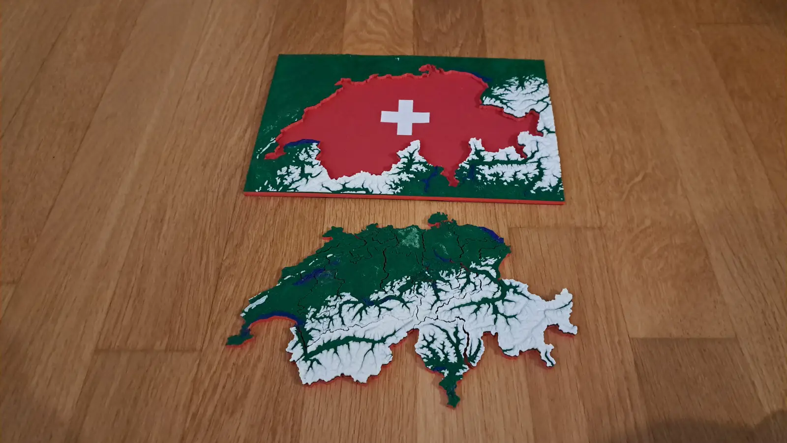 The first multicolour Switzerland puzzle, green and white, lying below its red tray with the Swiss cross