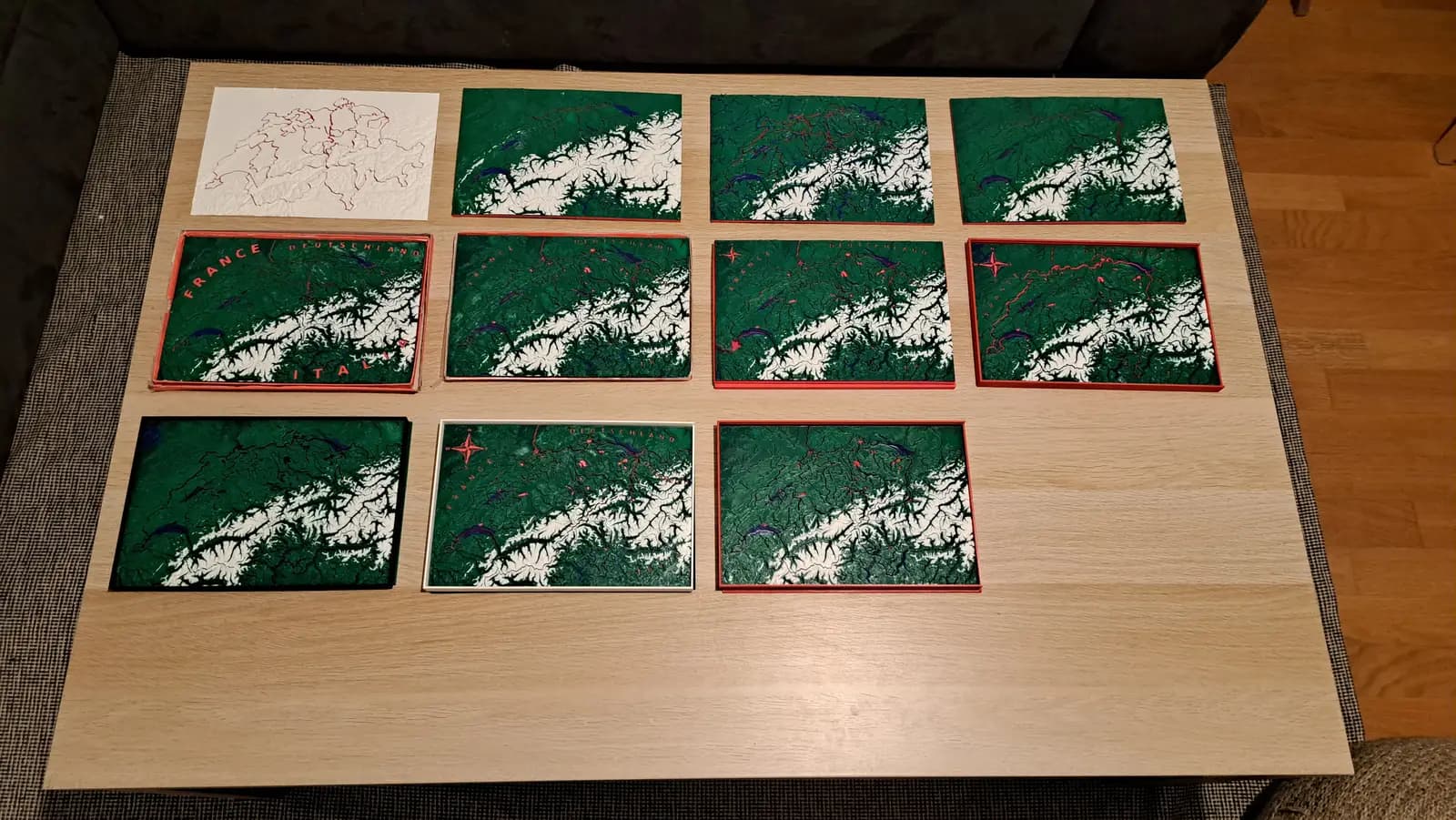 Ten finished green and white Switzerland plates laid out in rows on a table