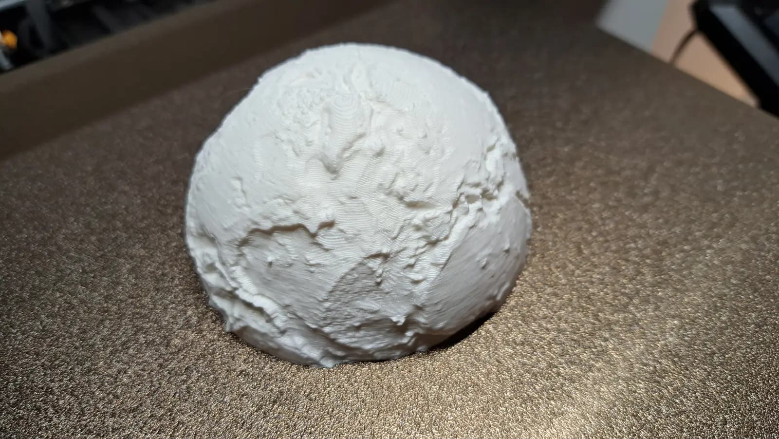 A white printed hemisphere of the globe with the continents in relief