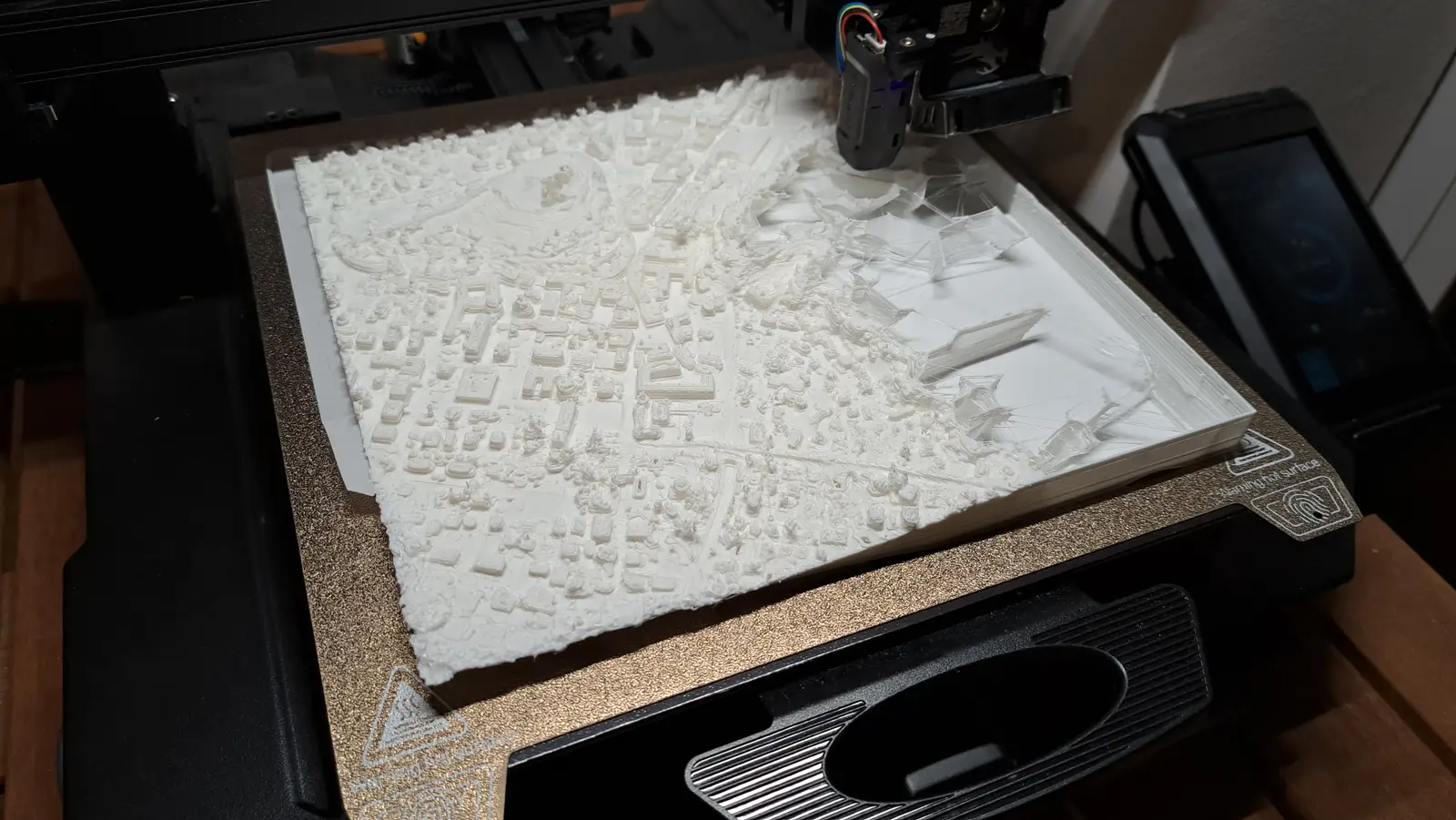 A white relief of a neighbourhood with every house printed, still on the print bed