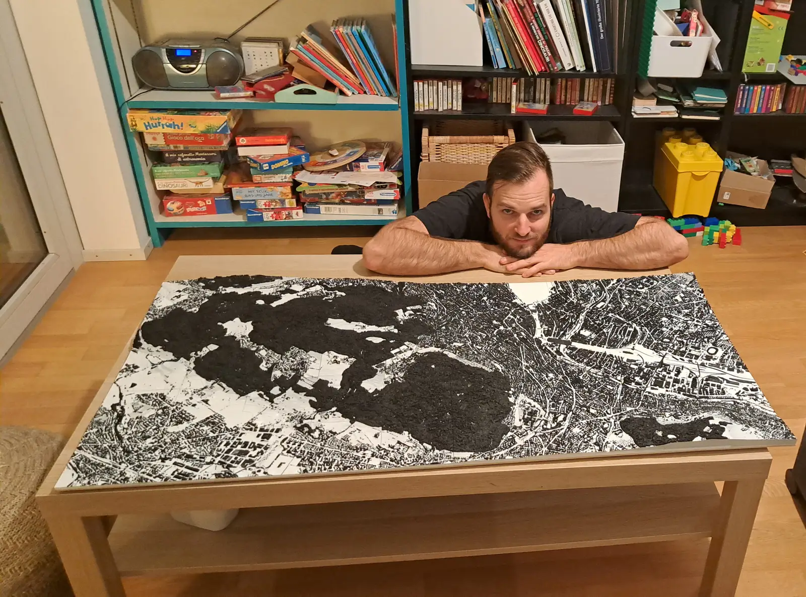 Nick leaning over a large black-and-white relief of Zürich laid across a living-room table